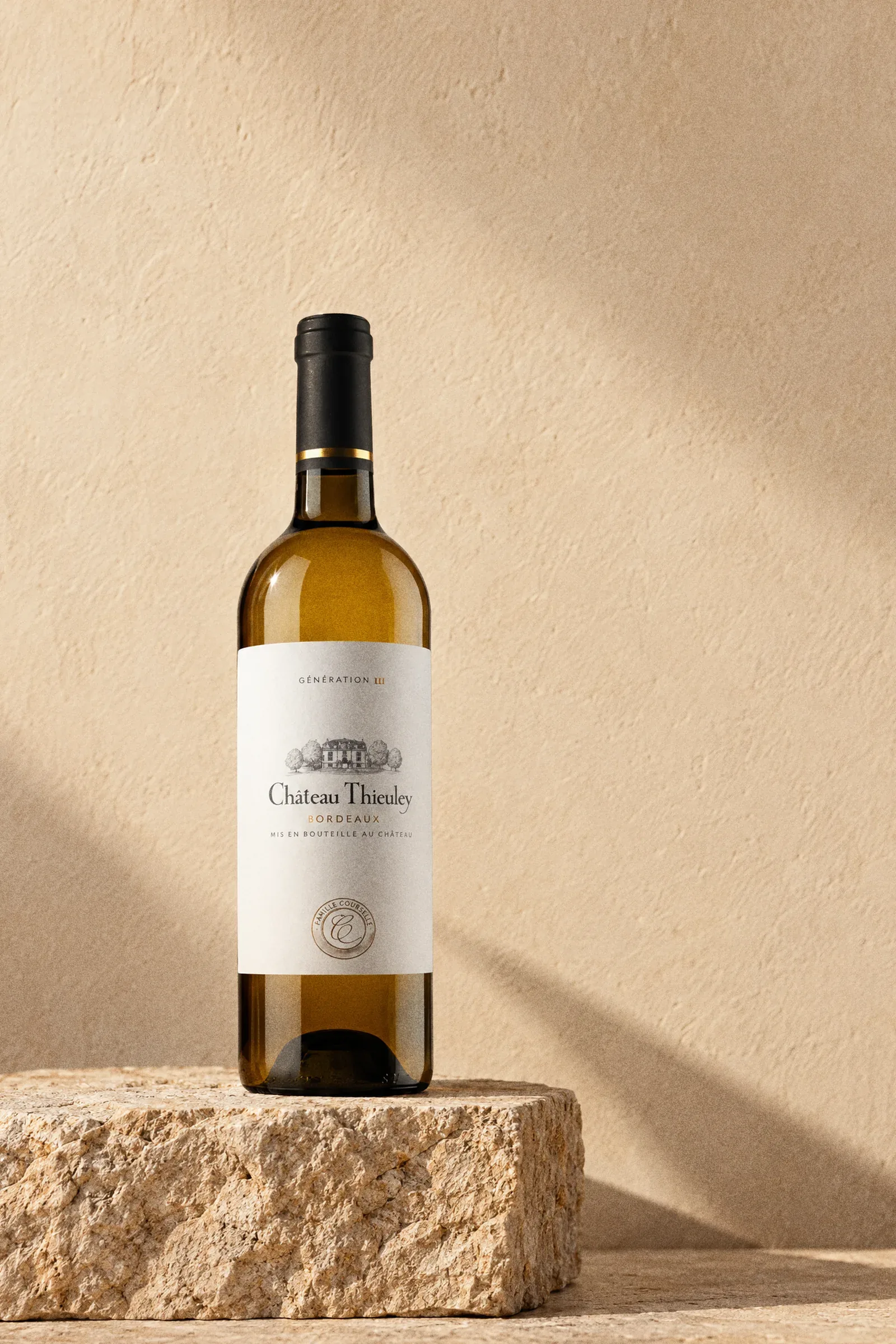 Château Thieuley 'Génération 3' Bordeaux Blanc 2023 bottle standing on a stone plinth in warm light